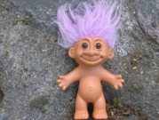A small plastic troll doll with purple hair. Looks like it's been introduced to a Van der Graaf generator.
